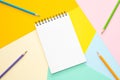 Spiral notebook with blank white sheet and colored pencils on multi-colored paper Royalty Free Stock Photo
