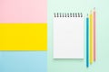 Spiral notebook with blank white sheet and colored pencils on multi-colored paper Royalty Free Stock Photo