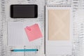 Squared open spiral notebook marker sticky note clip smartphone envelope lying wooden retro vintage rustic old