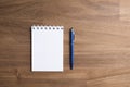 Spiral notebook, opened on a blank page, next to a blue pen, on a wooden desk Royalty Free Stock Photo