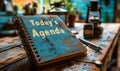 Spiral notebook with Todays Agenda on the cover, accompanied by a pen on a wooden surface, representing organization and Royalty Free Stock Photo