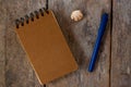 Spiral notepad craft cover and pen on wooden background. Empty sketchbook top view photo. Brown paper notepad