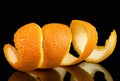 Spiral orange peel on black background. Citrus zest Royalty Free Stock Photo
