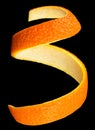 Spiral orange peel on black background. Fresh citrus twist