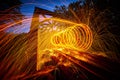 Spiral of orange steel wool sparks on train tracks with bridge Royalty Free Stock Photo