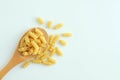 Spiral pasta noodles on wooden spoon and scattering. White background Royalty Free Stock Photo