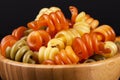 Spiral pasta trottole tricolore isolated in wooden bowl