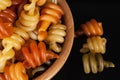 Spiral pasta trottole tricolore isolated in wooden bowl