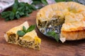 Spiral pie made of filo dough, spinach and feta cheese on wooden background.