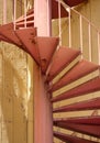 Spiral red stairs outside a yellow color painted building