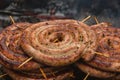 Spiral-rolled sausages ready to eat, grilled or roasted in a barbecue on an open fire and flames Royalty Free Stock Photo