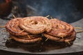 Spiral-rolled sausages ready to eat, grilled or roasted in a barbecue on an open fire and flames Royalty Free Stock Photo