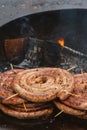 Spiral-rolled sausages ready to eat, grilled or roasted in a barbecue on an open fire and flames Royalty Free Stock Photo