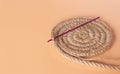 Spiral round jute napkin and crochet hook on beige background. Hobbies, needlework