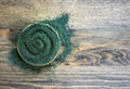 Spiral-shaped chlorella or spirulina powder on a dark wooden background with a copy space
