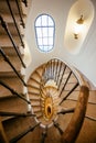 Spiral staircase in interior of historical house. Old architecture with stairs, window and space between floors