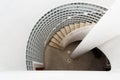 Spiral staircase with a view down into a white shaft with glass blocks and banisters