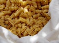 Spiral yellow pasta in a white fabric bag close up