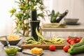 Spiralizer with zucchini noodles and vegetables on kitchen table