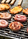 Spirals of spicy sausage grilling on a barbecue grilling over the hot coals outdoors in the garden or park on a summer picnic.