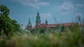 Spire and belltower of Wawel castle in Krakow city, rising up from the green grass up towards the blue sky.. Wide panorama of Royalty Free Stock Photo