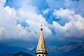 Spire of medieval catholic cathedral on background of stormy sky, dramatic clouds and mountain ranges. Saint Ivan Church in old to Royalty Free Stock Photo