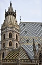 Spire and roof, with beautiful colored tiles, of the cathedral of Vienna, with a hat of veiled blue sky.