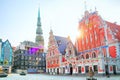 Spire of Saint Peter church left and House of the Blackheads right in the morning, Riga, Latvia. Sun rays. Royalty Free Stock Photo