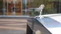 Spirit of Ecstacy or Emily logo on the hood of a rolls Royce. and bride the background. Emmy or Spirit of Ecstacy, hood