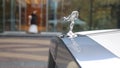 Spirit of Ecstacy or Emily logo on the hood of a rolls Royce. and bride the background. Emmy or Spirit of Ecstacy, hood