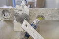 Spirit level with parts of other plastering tools on a metal plate under the plaster splashes