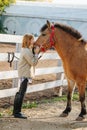 Spirited ginger girl holding horse`s snout, touching horse`s head with her face