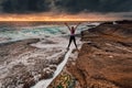 Spirited girl standing over rock crevice as waves wash in Royalty Free Stock Photo