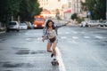 Spirited woman riding on a skateboard on an empty city road early in morning Royalty Free Stock Photo