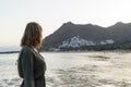Spiritual adolescent in green dress admire the sunset and the sea town on a hill in Tenerife. Blonde romantic woman look the