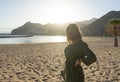 Spiritual adolescent in green dress admire the sunset and the sea town on a hill in Tenerife. Blonde romantic woman look the
