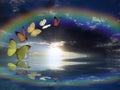 Spiritual background for meditation with butterflies, stormy clouds and rainbow in sea reflection Royalty Free Stock Photo