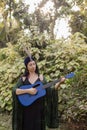 Spiritual development. Brunette in turban decorated with feathers stands with guitar in her hands. Royalty Free Stock Photo