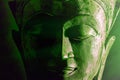 Spiritual enlightenment. Green buddha face statue close-up. Bold graphic image