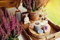 Spiritual home balcony decor with heather flowers, candlelight flame, crystal geodes, crystal wire tree and small Buddha figurine.