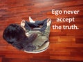 Spiritual inspirational quote - Ego never accept the truth. With young woman praying in meditation pose on the wooden floor.