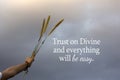 Spiritual inspirational quote - Trust on Divine and everything will be easy. With hand holding bunch of flower plant on blue sky.