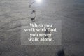 Spiritual inspirational quote - When you walk with God, you never walk alone. With footprints on beach black sand background. Royalty Free Stock Photo