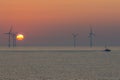 Spiritual landscape. Offshore wind turbines. Peaceful orange sky sunrise scene