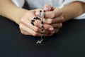 Spiritual prayer to god, with verve or rosary in the hands of a young girl. Black background. Close-up Royalty Free Stock Photo