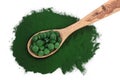 Spirulina algae powder and pills in wooden spoon isolated on white background. Top view Royalty Free Stock Photo