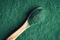 Spirulina algae powder on a spoon on green background