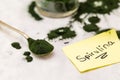 Spirulina green powder on single spoon with handwritten spirulina word