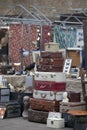 Spitalfields Antic Market. Sale of old suitcases that lie on each other. Stuffed crow on a stand in the background of old fabric