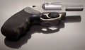 A 44spl stainless steel revolver laying upon a glass surface